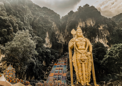 Der Eingang zu den Batu Höhlen in der Nähe von Kuala Lumpur. Mittig die Treppe zum Höhleneingang, Rechts im Bild eine große goldene Statue eines hinduistischen Gottes