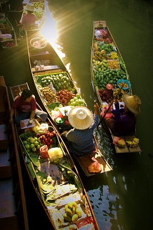 Ein schwimmender Markt in Thailand. Zwei Frauen verkaufen Früchte von ihren Booten aus